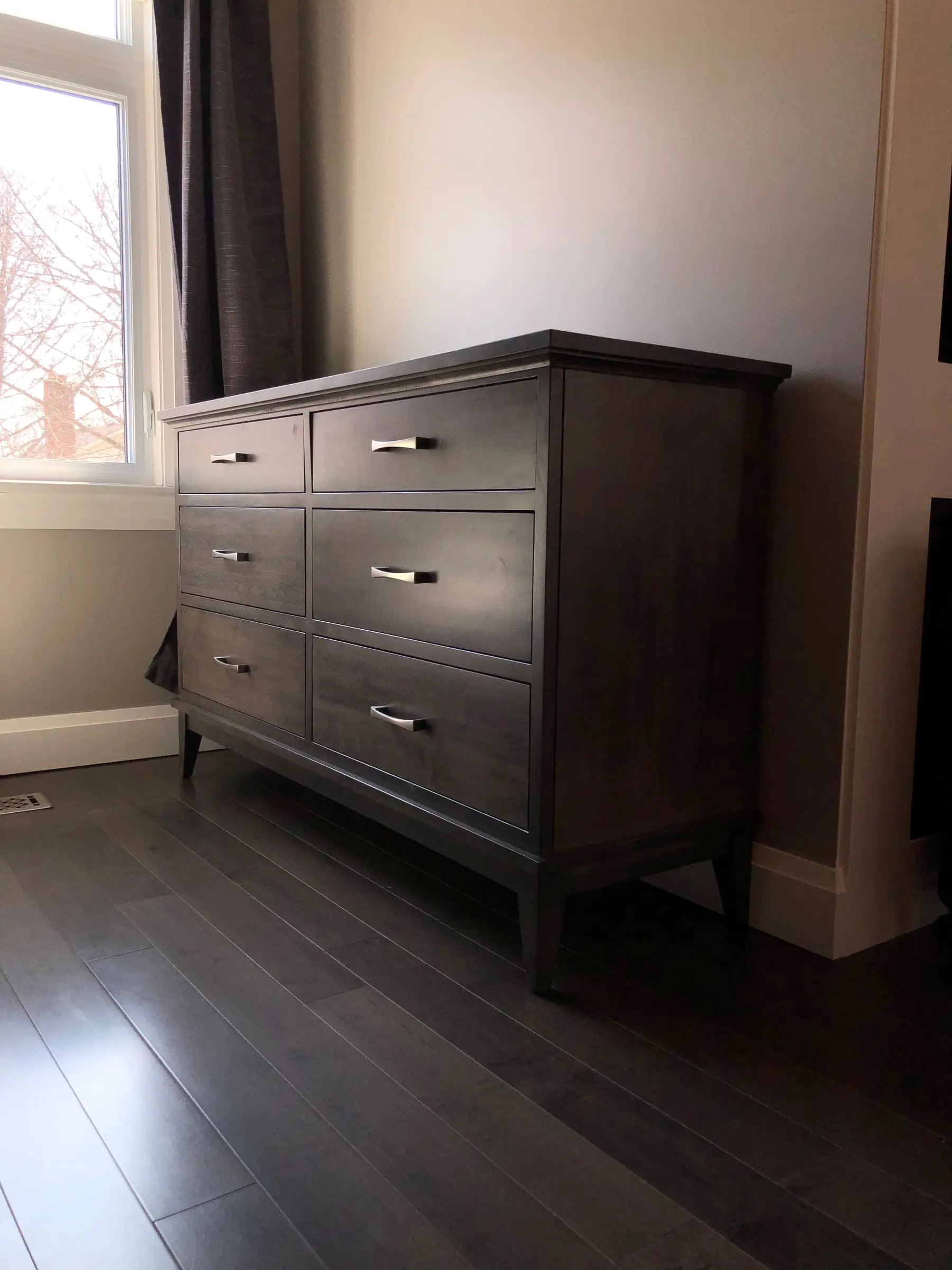 Custom dark-stained solid wood dresser installed beside a bedroom window
