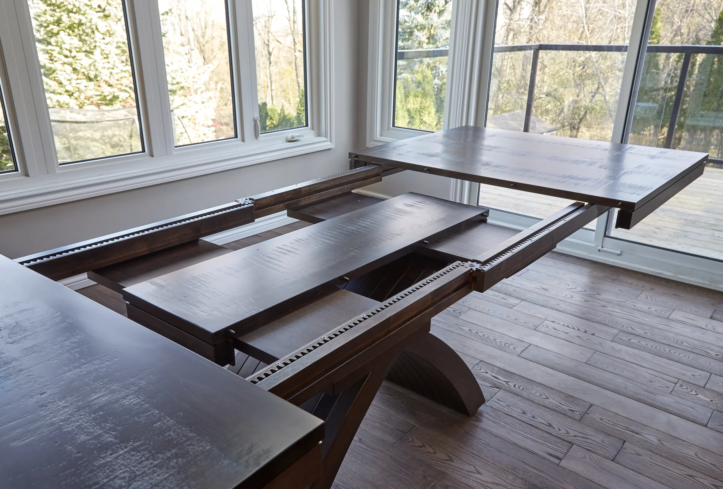 Custom solid wood dining table with its extension mechanism open in a bright Ontario home