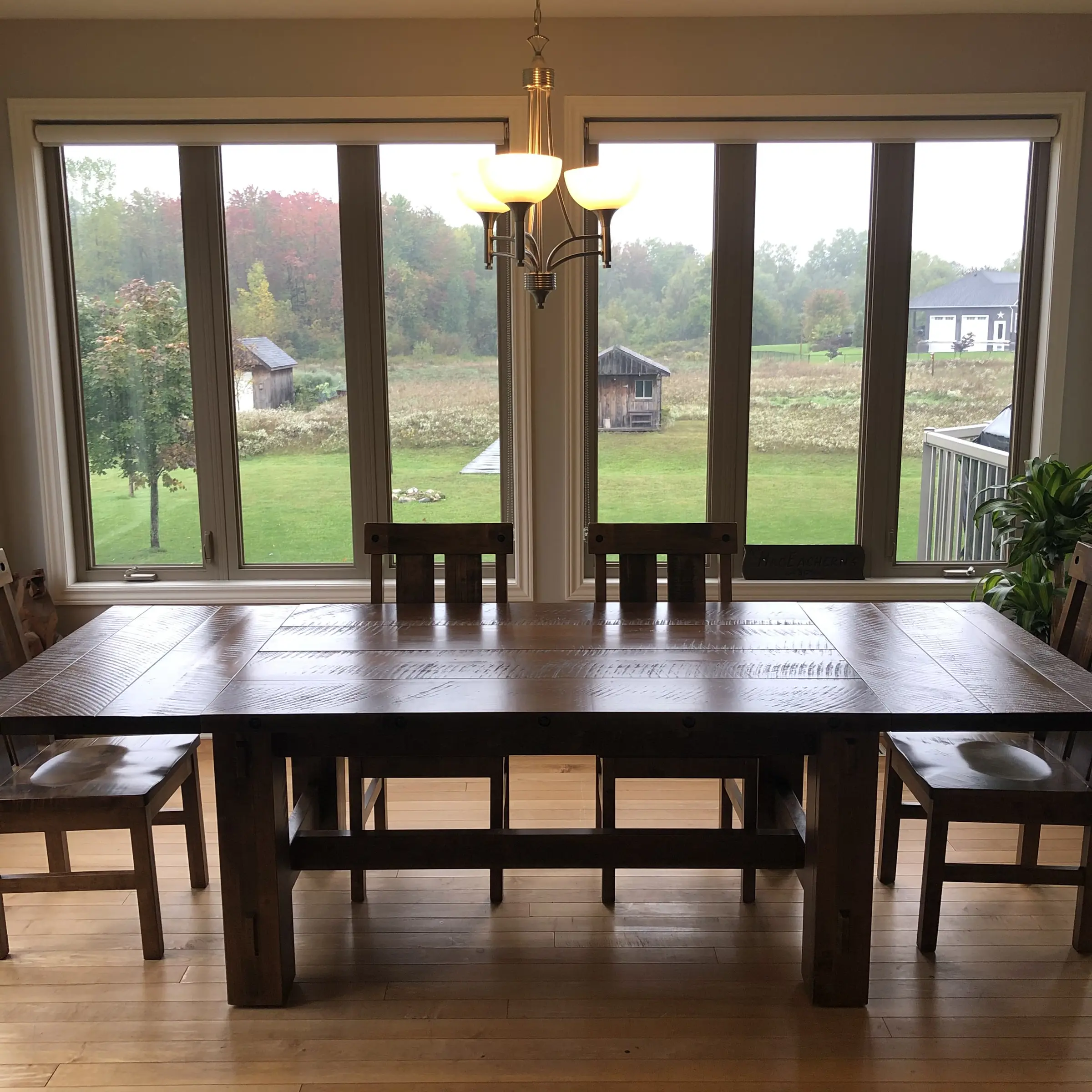 Custom solid wood dining table with matching benches in front of large windows