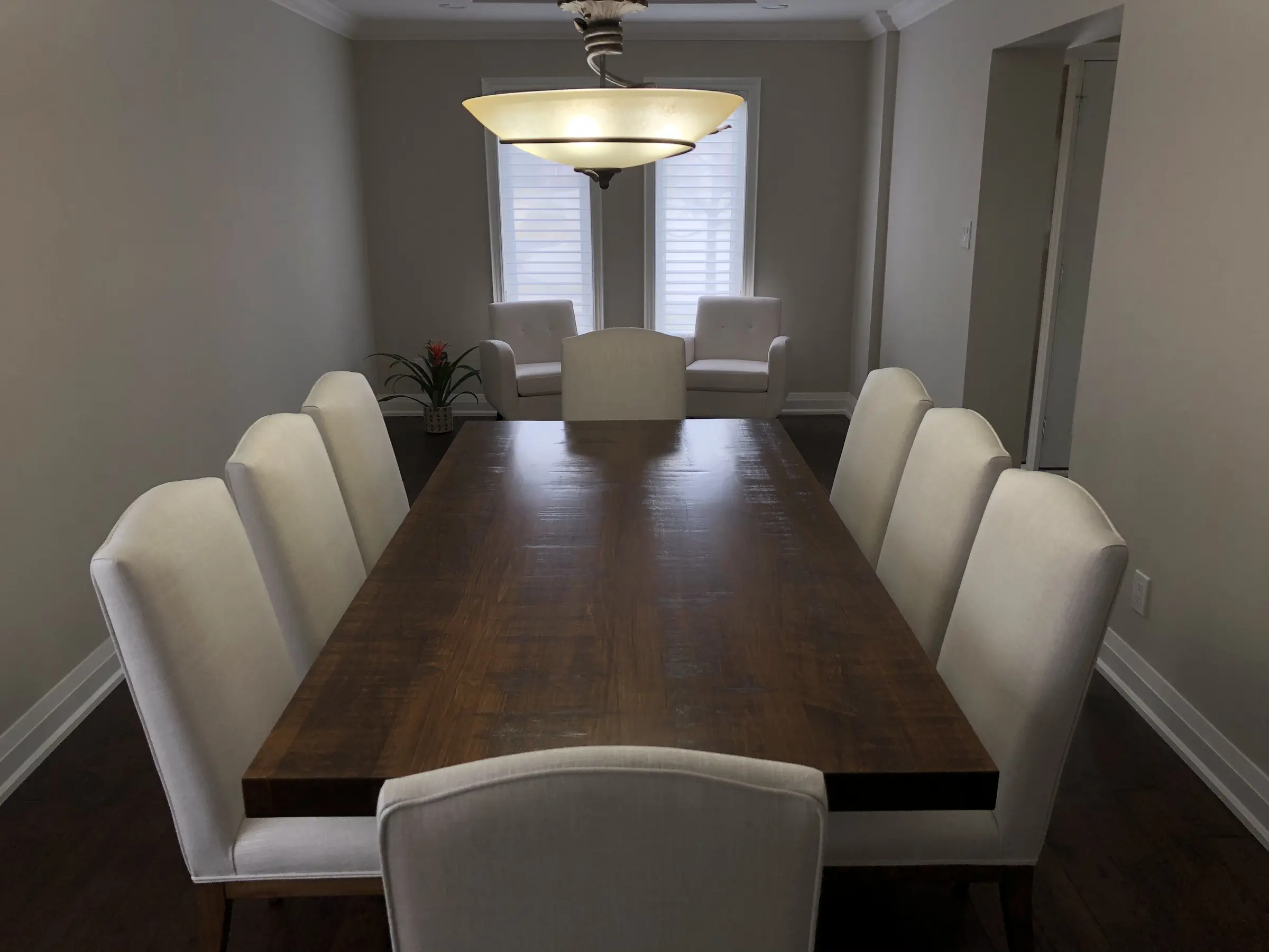 Modern solid wood dining table surrounded by light upholstered chairs