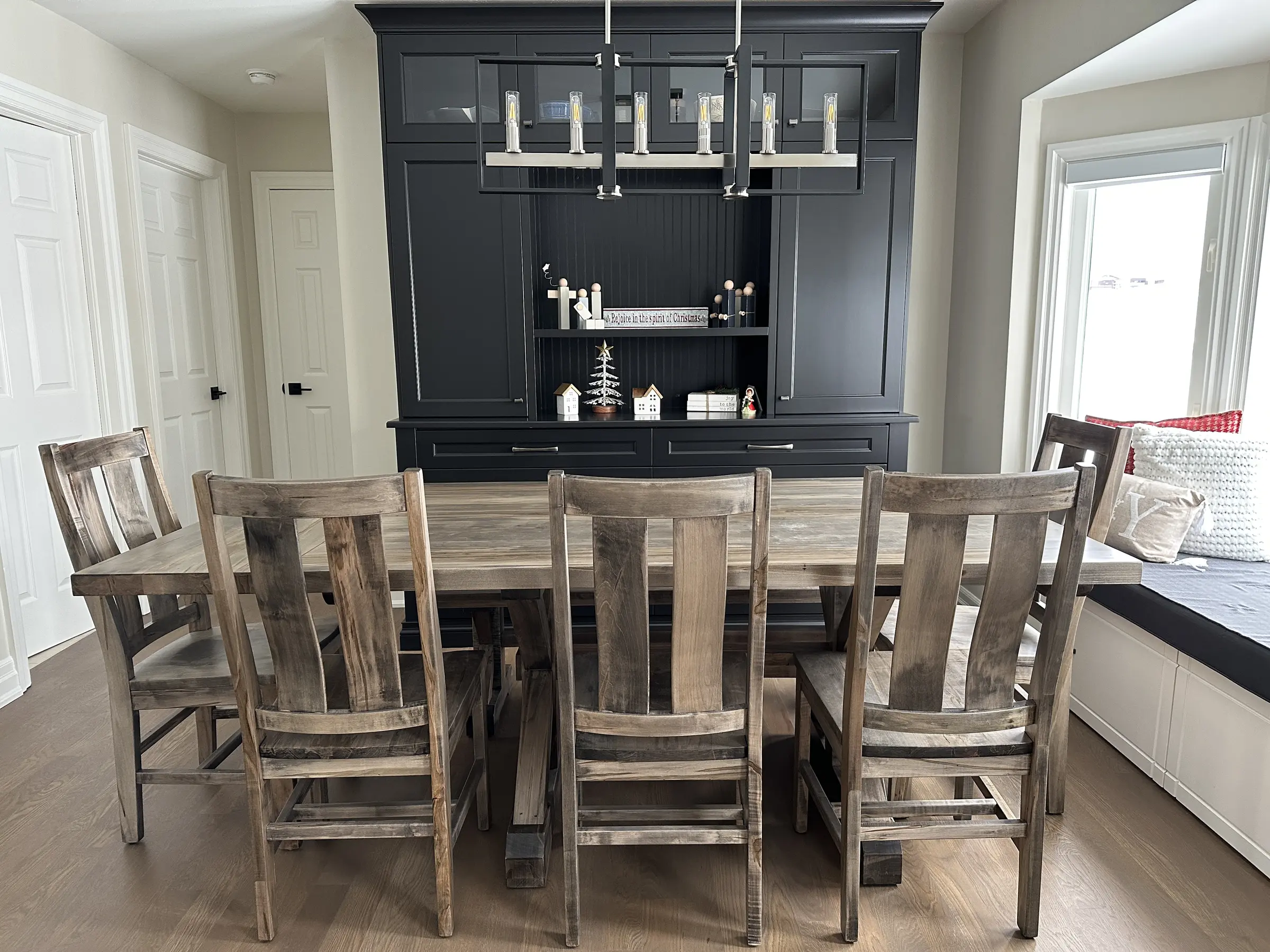 Rustic solid wood dining set installed in front of a dark custom hutch