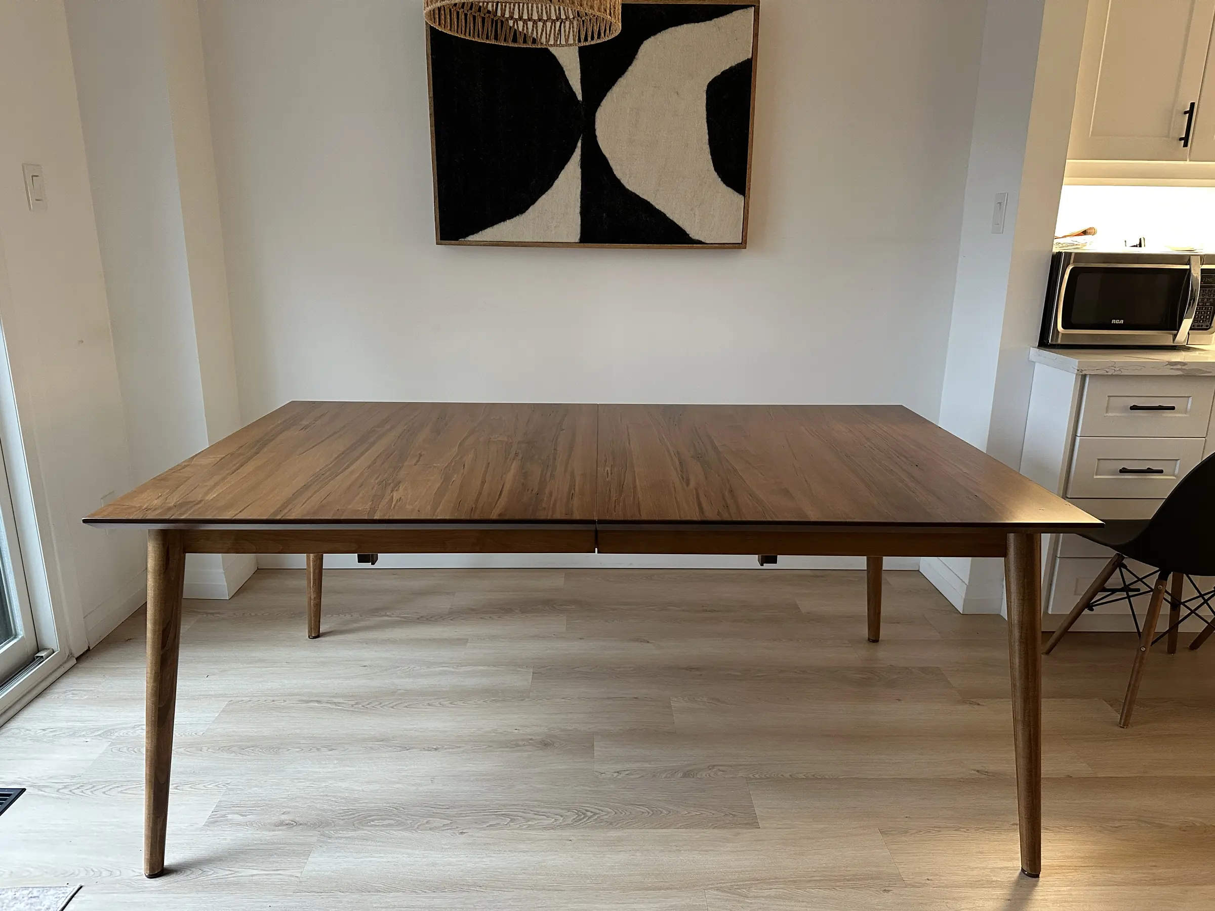 Slim-leg solid wood dining table displayed in a modern open home